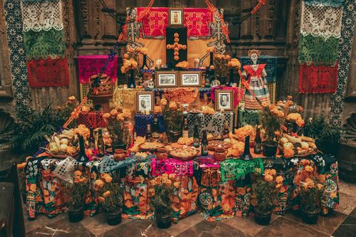 In The Day of the Dead, or Día de los Muertos in Spanish, they build altars, known as ofrendas, with flowers, candles, photos, and food the deceased enjoyed in life.